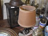 a table with a lamp, a clock, and other items on it