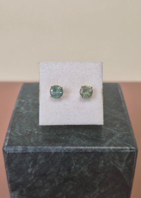 a close up of a pair of green earrings on a white card