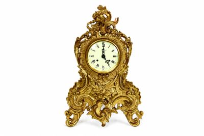 une horloge dorée posée sur un socle, sur fond blanc