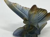statue of a bird with a flower on its head on a white surface