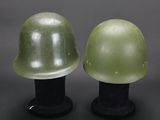 two green helmets sitting on top of each other on a black surface