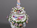 a close up of a vase with a figurine on top of it
