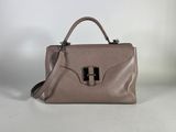 a brown handbag sitting on top of a table next to a white wall