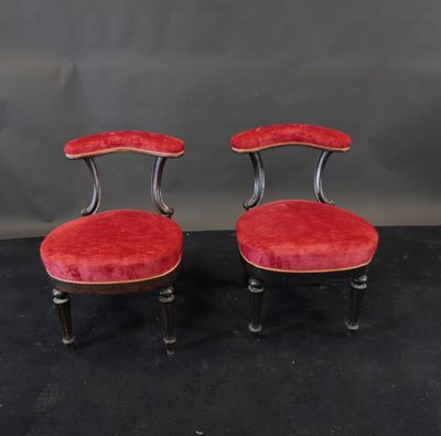 a pair of red velvet chairs with black legs