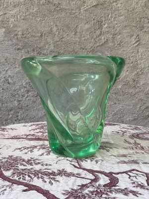 un vase en verre vert posé sur une table recouverte d'une nappe rouge et blanche