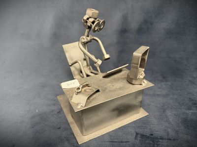 a metal sculpture of a man sitting at a desk with a computer
