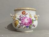 a white vase with a pink rose on it on a table