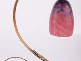 brass table lamp with a pink glass shade and a black cord