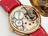 a watch that is sitting on a red leather strap