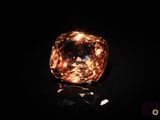 an orange diamond on a black surface with a black background