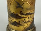 a gold vase with a bird on it on a stand