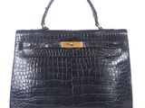 a black crocodile skin handbag with gold hardware on the handle