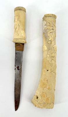 two pieces of carved ivory and a knife on a white surface