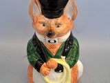 une figurine représentant un chat coiffé d'un chapeau et tenant une banane