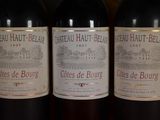 three bottles of red wine are lined up on a shelf