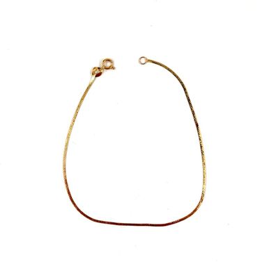 un gros plan d'un bracelet plaqué or sur fond blanc