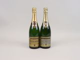 two bottles of champagne sitting next to each other on a white surface