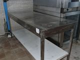 une table en acier inoxydable sur laquelle est posé un micro-ondes, dans une cuisine