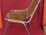 a metal chair with a wooden seat on a red surface