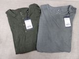 pair of men ' s t - shirts with tags on them sitting on a couch