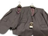 two suits hanging on a hanger on a white wall