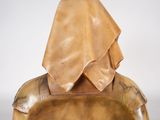 bronze sculpture of a woman sitting on a chair with a hood over her head