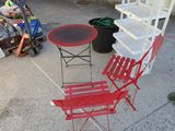 a red chair and a red table on the sidewalk