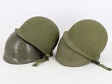 two army green helmets sitting next to each other on a white surface