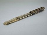 an old pen with writing on it sitting on a white surface