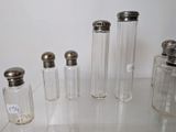 five glass jars with silver lids on a glass table