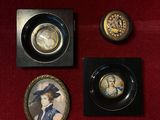 three miniature pictures of a woman in a hat and other items on a red cloth