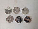 six different coins are shown on a white surface with a white background