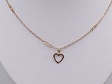 un gros plan sur un collier avec un cœur en or porté par un mannequin