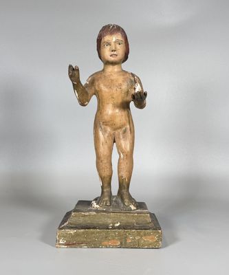une statue ancienne représentant un garçon tenant une balle, posée sur un socle en bois