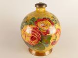 a yellow vase with red and yellow flowers painted on it