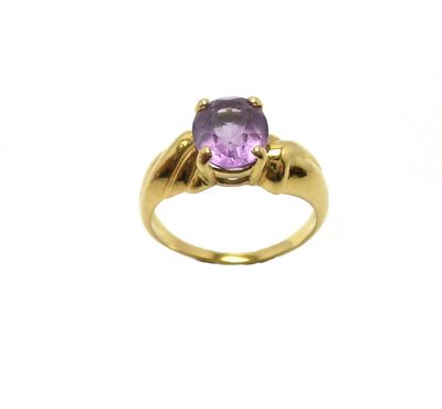 gros plan d'une bague en or avec une pierre violette