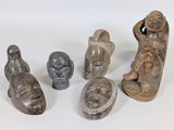 plusieurs figurines sculptées de formes et de tailles variées, posées sur une surface blanche