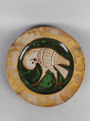 une assiette sur laquelle est représenté un oiseau, sur un fond blanc