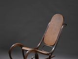 un vieux fauteuil à bascule avec une assise en osier sur fond gris