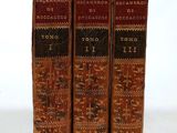 three old books sitting on top of each other on a white surface