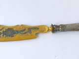 a close up of a knife on a table with a white background