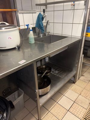 a kitchen with a stove, sink, and a pot on the counter