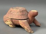 une image représentant une boîte en forme de tortue avec un couvercle, posée sur une surface grise
