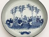a blue and white plate with a picture of a group of people on it