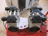 two air compressors sitting on top of a red tank