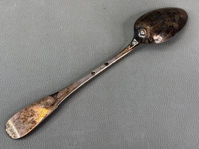 silver spoon with a face on it sitting on a gray surface