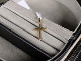 une petite croix en or dans un écrin posé sur une table