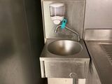 un évier dans un coin de la cuisine, avec une poubelle bleue