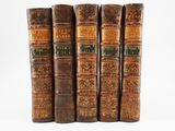four old books sitting on top of each other on a white surface