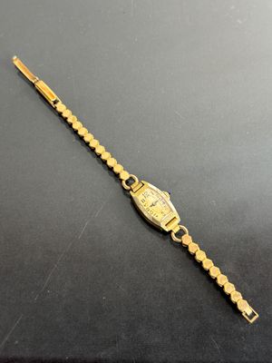 an image of a gold wrist watch on a black surface